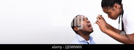 Medico donna Controllo dell'uomo mal di gola con abbassa lingua su sfondo bianco Foto Stock