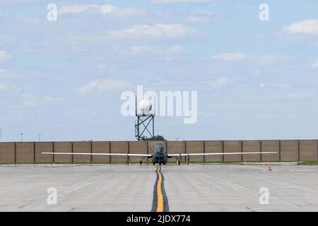 Gli airmen assegnati al 319th Aircraft Maintenance Squadron dalla base dell'aeronautica di Grand Forks, North Dakota, rimorchiano un RQ-4 Block 30 Global Hawk pilotato a distanza aereo 6 giugno 2022, attraverso la linea di volo della base dell'aeronautica di Grand Forks per Northrop Grumman a Grand Sky. Questo è stato il primo dei cinque blocchi RQ-4 30s ad essere trasferiti a Grand Sky per essere dotati di diverse tecnologie di sensori e iniziare a operare come parte del reparto Test System Test del Centro di Gestione risorse di prova. Situato sulla base dell'aeronautica di Grand Forks, il Grand Sky è un parco di affari e di aviazione focalizzato sullo sviluppo e lo sviluppo di Foto Stock