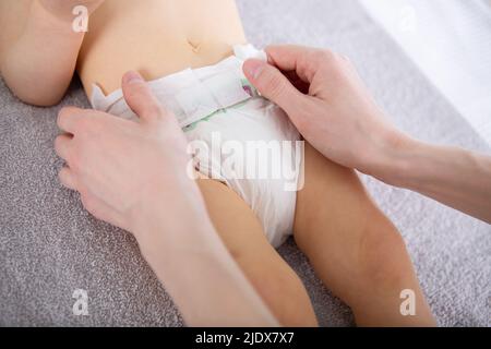 le mani stanno cambiando il pannolino dei babys Foto Stock