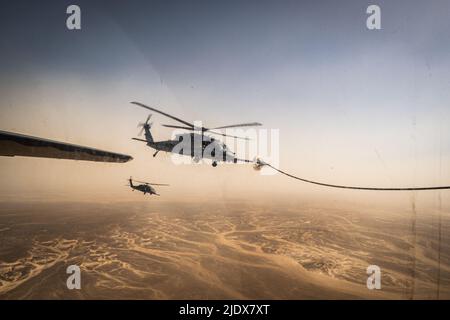 Un elicottero 332d Air Expeditionary Wing HH-60G Pave Hawk riceve carburante da un aereo HC-130J Combat King II, anch'esso assegnato al 332d AEW, nel sud-ovest asiatico 12 giugno 2022. La missione principale del Pave Hawk è quella di condurre operazioni di recupero del personale diurne o notturne in ambienti ostili per recuperare personale isolato durante il conflitto. L'HH-60G è inoltre incaricato di eseguire operazioni militari diverse dai conflitti, comprese la ricerca e il salvataggio civili, l'evacuazione medica, la risposta alle catastrofi, l'assistenza umanitaria, la cooperazione in materia di sicurezza/consulenza in materia di aviazione; Supporto di volo spaziale della NASA, e salvataggio c Foto Stock