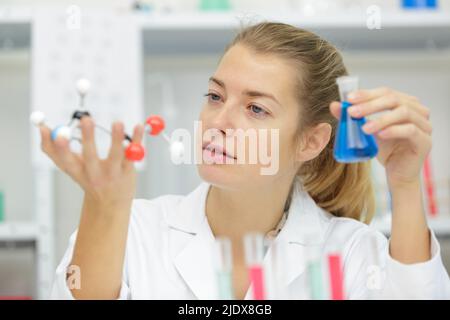 scienziato femminile che detiene il modello di dna e il pallone di vetro Foto Stock