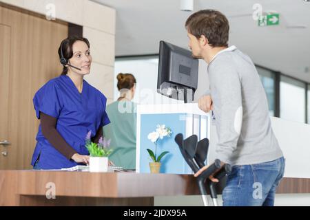 uomo che parla con l'infermiera femminile del suo appuntamento in ospedale Foto Stock