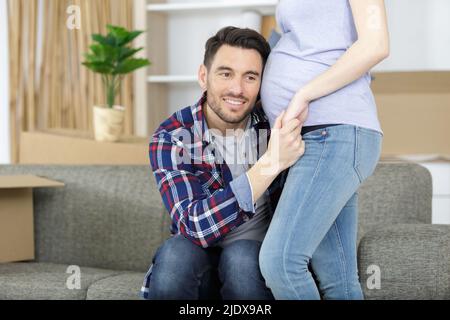 buon giovane uomo che mette l'orecchio al ventre incinta del womans Foto Stock