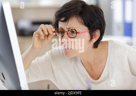 donna d'affari in occhiali fissando il suo computer Foto Stock