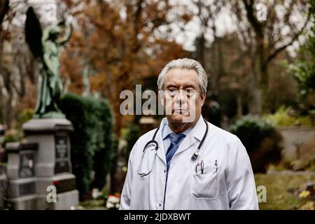 Medico senior che indossa un camice da laboratorio in piedi sul cimitero Foto Stock