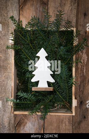 Legno decorazione dell'albero di Natale che giace in gabbia riempita con ramoscelli di conifera Foto Stock