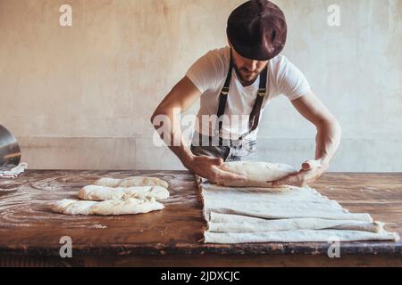 Panettiere arrangiare l'impasto su tovagliolo in panetteria Foto Stock