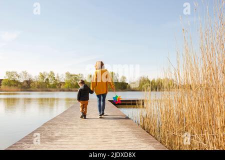 Madre e figlio camminano sul molo sopra il lago Foto Stock