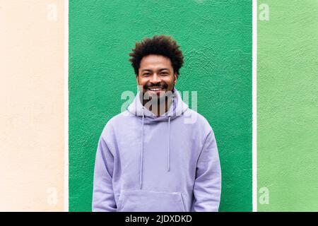 Uomo sorridente davanti al muro verde Foto Stock