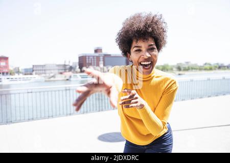 Donna allegra con acconciatura afro gesturing godendo al lungomare Foto Stock