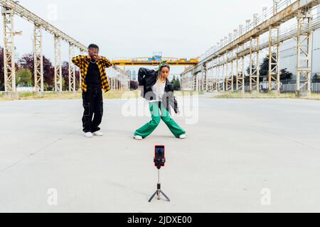 Giovane donna che filma il video di danza attraverso lo smartphone sul sentiero Foto Stock