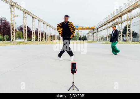 Il giovane filma il video della danza attraverso lo smartphone sul sentiero Foto Stock