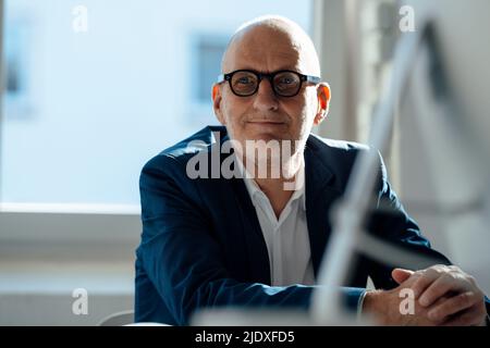 Uomo d'affari sorridente che indossa occhiali seduti in ufficio Foto Stock