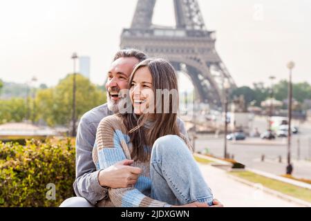 Coppia allegra e matura seduta insieme di fronte alla Torre Eiffel, Parigi, Francia Foto Stock