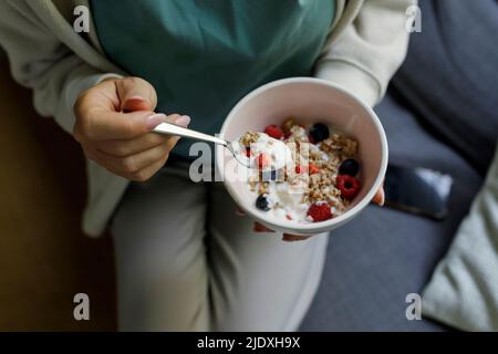 Donna che tiene ciotola di yogurt e muesli Foto Stock