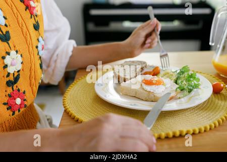 Le mani della donna che tiene il coltello da tavolo e la forcella dalla piastra sul tavolo Foto Stock