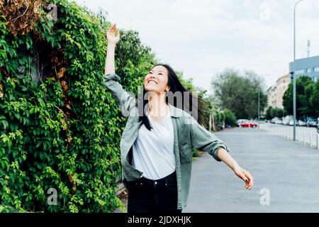 Felice giovane donna con mano alzata godendo da piante Foto Stock