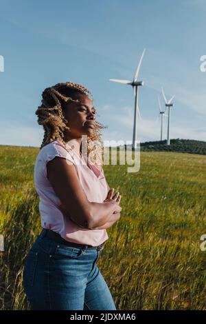 Donna sorridente con le braccia incrociate in piedi nel prato Foto Stock