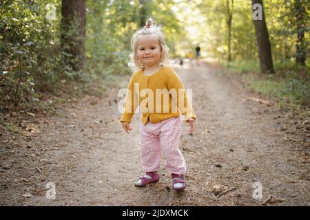 Sorridente ragazza bionda carina sul sentiero in foresta Foto Stock