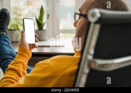 Uomo d'affari maturo che usa il telefono cellulare in ufficio Foto Stock