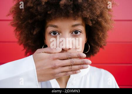 Giovane donna che copre la bocca con la mano Foto Stock