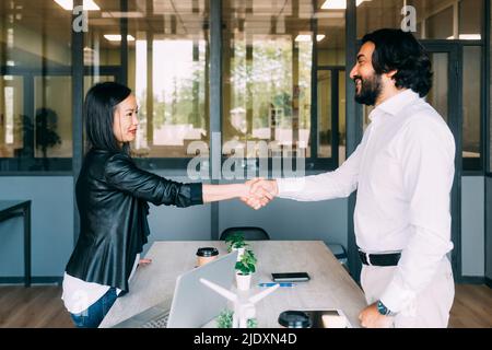 Sorridenti uomini d'affari che scuotono le mani dopo una riunione in ufficio Foto Stock