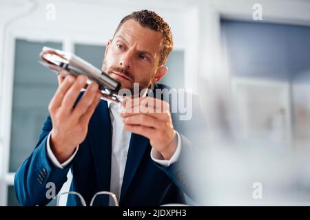Un uomo d'affari concentrato che esamina il modulo di riscaldamento in ufficio Foto Stock