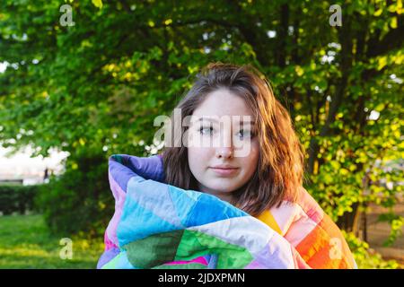 Ragazza adolescente avvolta in coperta colorata trapunta al parco Foto Stock