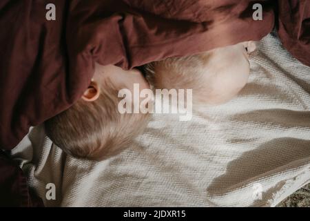 I fratelli dormono sotto la coperta marrone sul letto Foto Stock