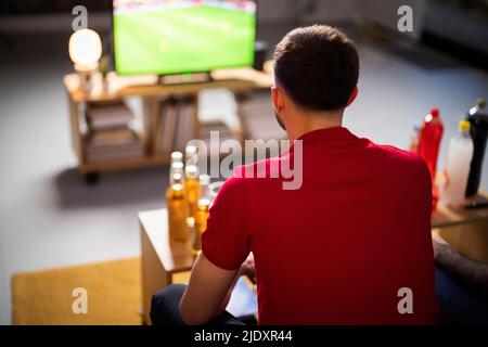 Giovane che guarda la partita di calcio a casa Foto Stock