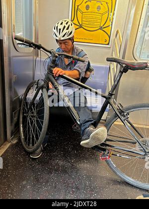 L'uomo stanco guida un treno della metropolitana con la sua bicicletta a Brooklyn, New York. Foto Stock