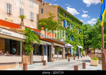 Un edificio coperto di edera su una strada di caffetterie e negozi nello storico villaggio di Old Grimaud sulle colline sopra Saint-Tropez, in Francia. Foto Stock