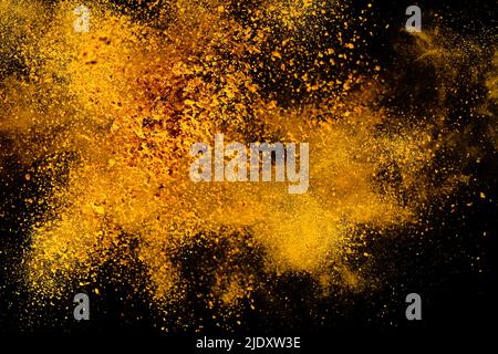 Esplosione, schizzi di curcuma su sfondo nero. India Seasoning. La polvere arancione della radice curmerica. Foto Stock