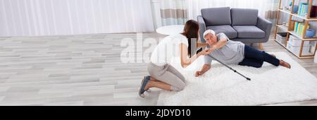 Donna aiutando il padre dopo la caduta su un tappeto a casa Foto Stock