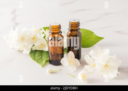 olio essenziale di fiori di gelsomino in due bottiglie mediche di vetro sullo sfondo di fiori. spa, aromaterapia, relax Foto Stock