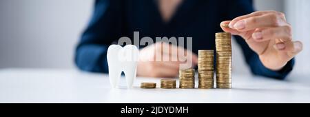 Donna che mette il cappotto sulla parte superiore delle monete della pila di fronte al dente bianco Foto Stock