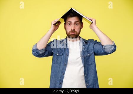 L'uomo triste sta mettendo il laptop sulla sua testa dopo aver trascorso molto tempo in rete. Dal tetto del notebook. Foto Stock