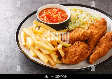 Pollo fritto fatto in casa con patatine fritte, insalata di cavolo e salsa piccante da vicino nel piatto sul tavolo. Orizzontale Foto Stock
