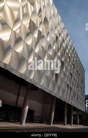 Design scultoreo contemporaneo, edificio rivestito in pannelli metallici formati nel 3D. I pannelli perforati nascondono le finestre. Architettura moderna. Foto Stock