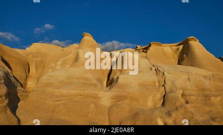 Luce del mattino, tufo, bizzarra formazione rocciosa, cielo blu scuro, nuvole bianche, Spiaggia di Sarakiniko, Isola di Milos, Cicladi, Grecia Foto Stock