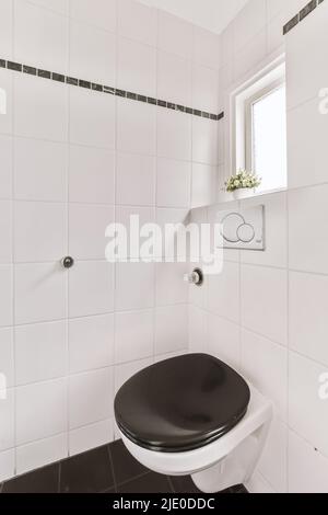 Armadio con lavatrice mechine in bagno piastrellato bianco con wc appeso alla parete Foto Stock