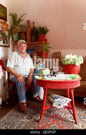 L'uomo anziano saluta gli ospiti con il vino di Madeira a Casa de Como, villaggio di Santana, abbreviazione di Santa Anna, Riserva della Biosfera dell'UNESCO, Madeira Foto Stock