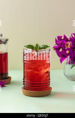 Tè di frutta rossa ghiacciata appena fatto su un tavolo verde Foto Stock