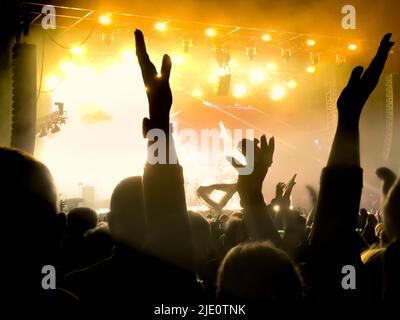 La folla si è esibita in un concerto di musica con il palco sullo sfondo. Foto Stock