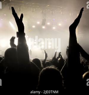 La folla si è esibita in un concerto di musica con il palco sullo sfondo. Foto Stock