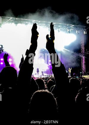 La folla si è esibita in un concerto di musica con il palco sullo sfondo. Foto Stock