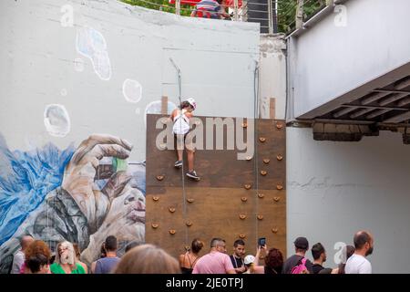 Giovane ragazza che sale su un muro con una corda per la sicurezza durante un evento Foto Stock