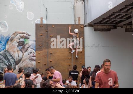 Giovane ragazza che sale su un muro con una corda per la sicurezza durante un evento Foto Stock