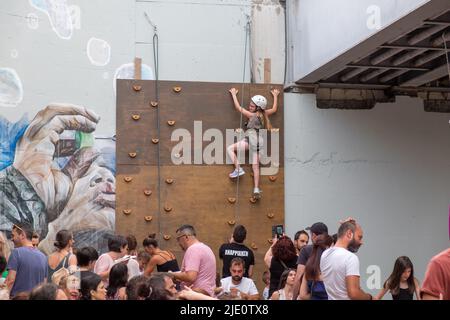 Giovane ragazza che sale su un muro con una corda per la sicurezza durante un evento Foto Stock