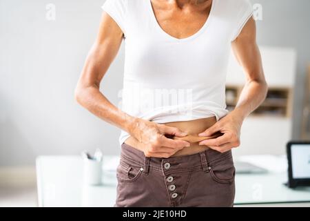 Liposuzione e dieta di grasso dello stomaco. Pizzico della pelle dello stomaco Foto Stock